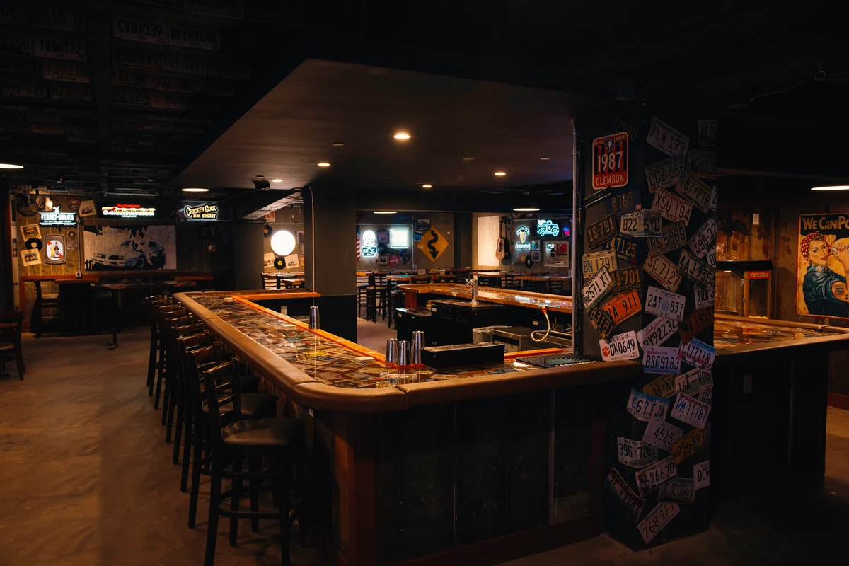 American Dive’s wooden bar, dark stools and license-plate-covered column