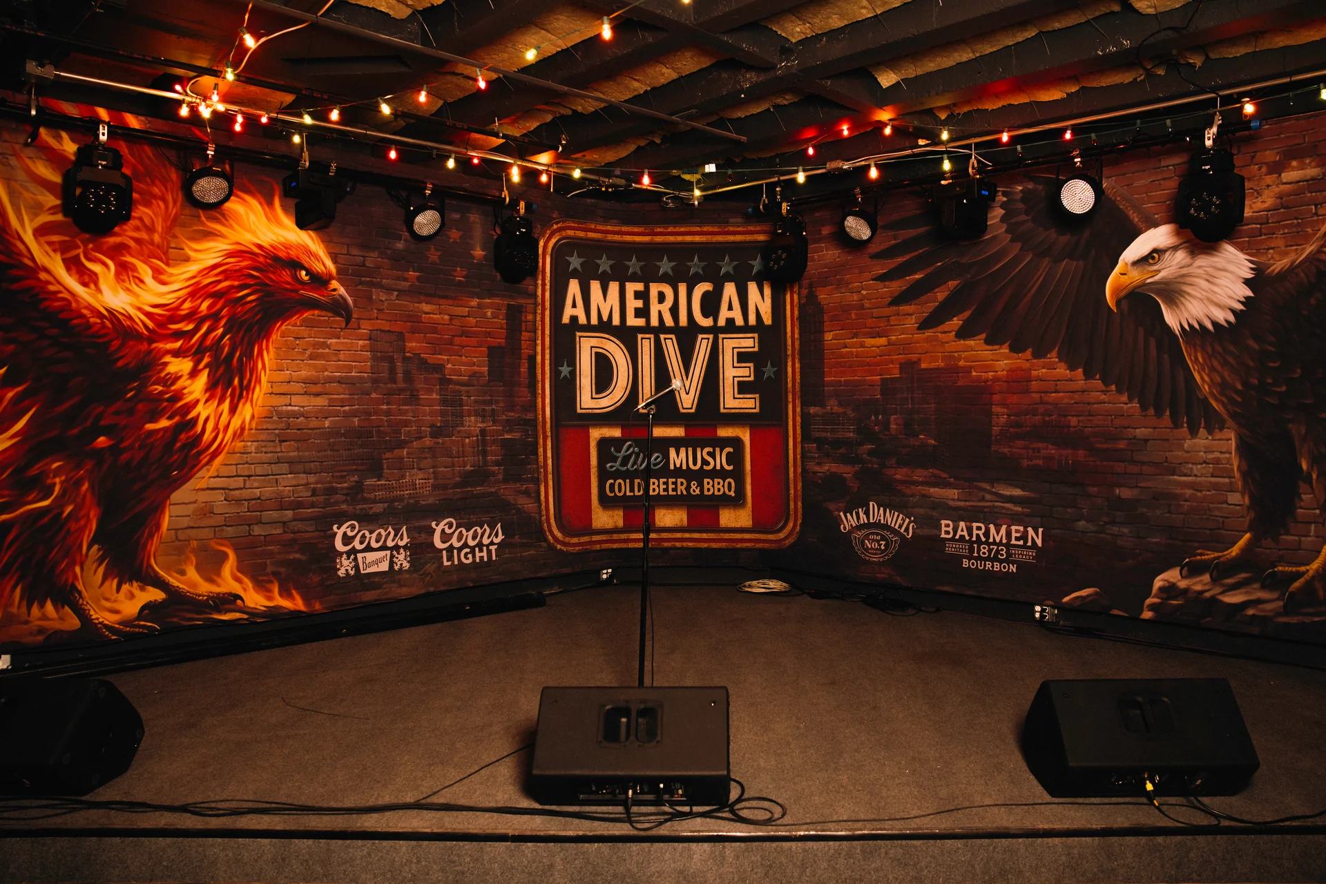 The American Dive music stage with instruments and an eagle mural
